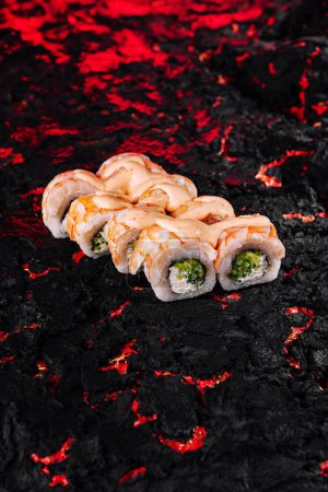Gourmet sushi rolls with spicy drizzle on a unique black lava textured background