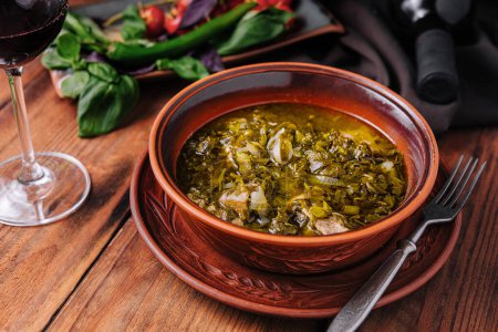 Traditional kale soup served in a handcrafted terracotta bowl, paired with wine and fresh vegetables