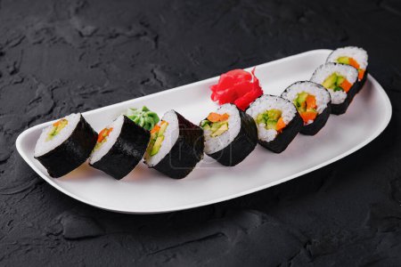 Selección de sushi con ingredientes frescos ingeniosamente exhibidos en un plato blanco moderno sobre un fondo oscuro
