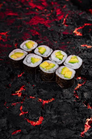 Des rouleaux de sushi à l'avocat exquis habilement présentés sur un fond texturé vibrant semblable à de la lave