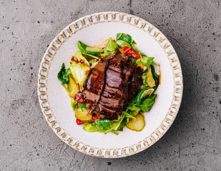 Savory beef steak served atop a fresh mixed greens salad, culinary presentation