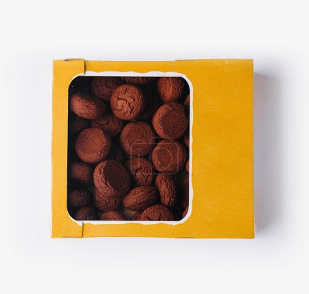Top view of a yellow box filled with rich, homemade chocolate truffle cookies isolated on white