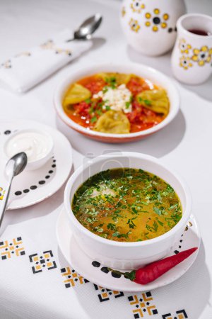 Un tazón de sopa fresca y casera y pasta servido en una mesa elegante con utensilios