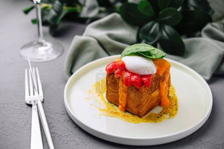 Foto de Elegante plato de brunch con un huevo escalfado encima de la tostada francesa con salsa de pimiento rojo - Imagen libre de derechos