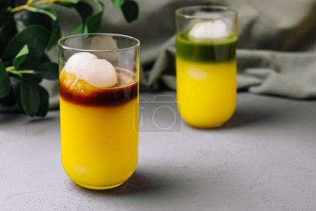 Elegant glasses with layered tropical cocktails and ice sphere