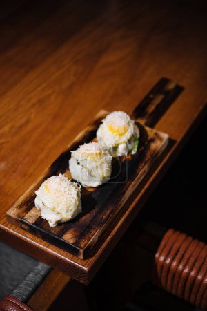 Wykwintne bułki sushi zwieńczone białą ikrą, podawane na wiejskiej drewnianej desce