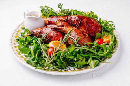 Delicious roasted quail with citrus garnish on a bed of fresh arugula, served on an ornate plate