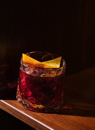 Classic cocktail adorned with a twist of citrus peel, presented in warm, intimate lighting