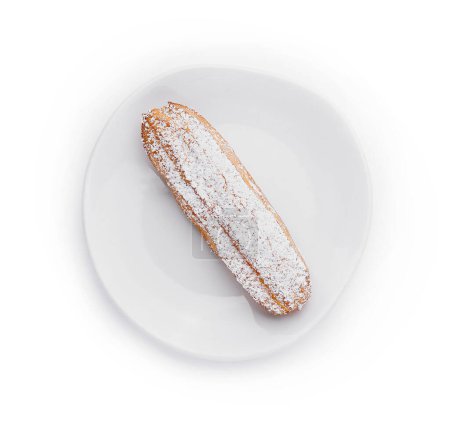 Appetizing eclair dusted with powdered sugar served on a pristine white plate