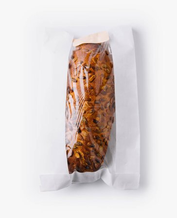 Top view of a rustic, crusty loaf of bread wrapped in a paper bag on a white background