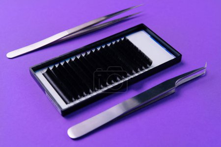 Pinzas de alta precisión y tiras de pestañas para extensiones, exhibidas en una vibrante superficie púrpura