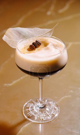 Téléchargez les photos : Martini expresso raffiné garni de grains de café et d'une feuille délicate, servi dans un verre classique - en image libre de droit