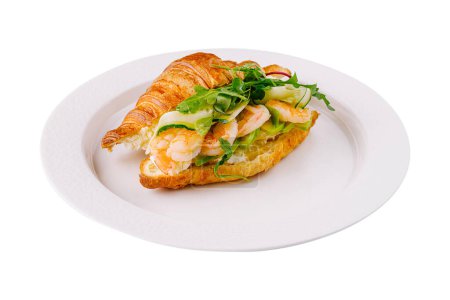 Delicious croissant sandwich filled with fresh shrimp, avocado, and greens, isolated on white