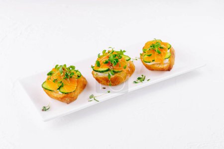 Photo for Elegant salmon canapes topped with microgreens on a white plate - Royalty Free Image