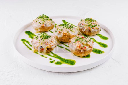 Elegant stuffed mushrooms with creamy filling served on a clean white plate, garnished with fresh herbs