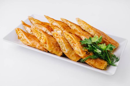 Golden puff pastry snacks on a white plate with a textured background