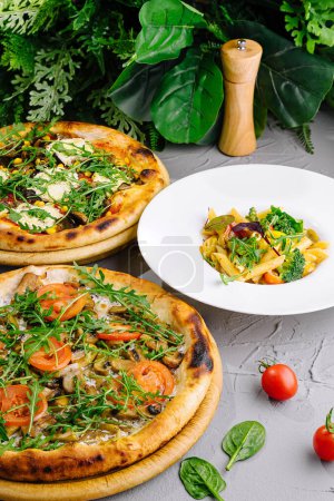 Artisanal pizzas with fresh toppings next to a plate of pasta, ready for a meal