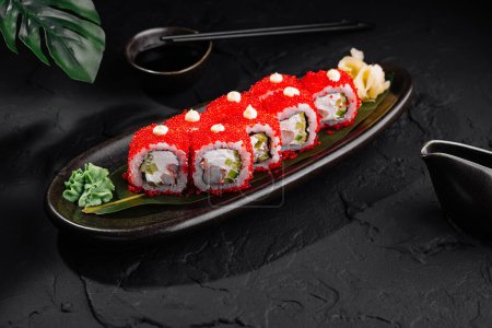 Elegancka bułka sushi pokryta czerwonym kawiorem, podawana z sosem sojowym i wasabi na eleganckiej czarnej talerzu