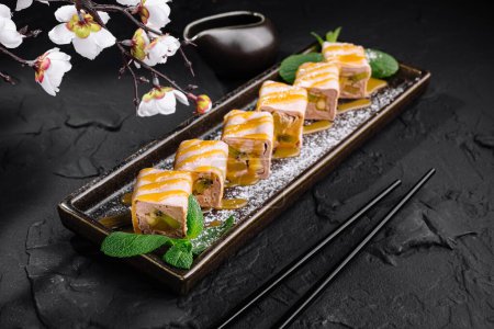 Elegantes rollos de sushi con kiwi y plátano servidos en un plato con una rama de sakura, sobre un fondo de piedra oscura