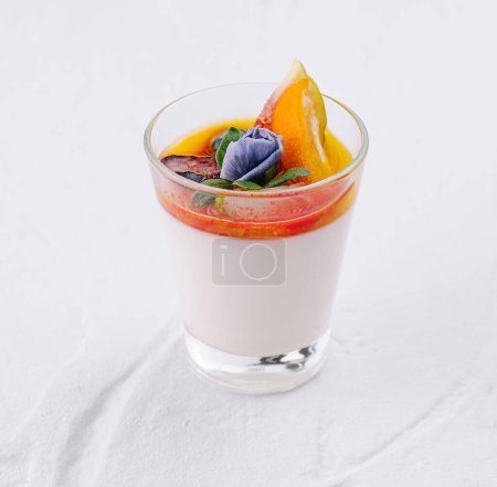 Elegante postre de panna cotta con colorida cobertura de frutas sobre un fondo blanco