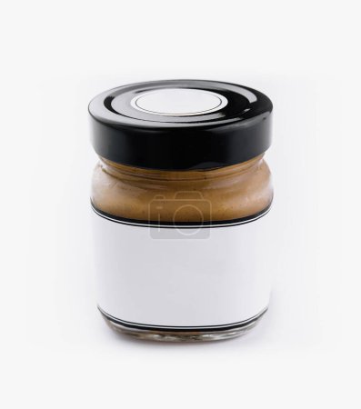 Clear glass peanut butter jar with blank label and black lid isolated on a white background