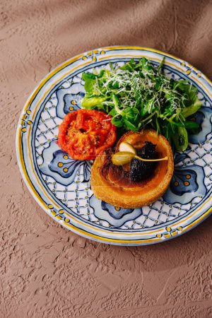 Elevated view of a delicious toast with tomato, greens, and spread on a designer plate