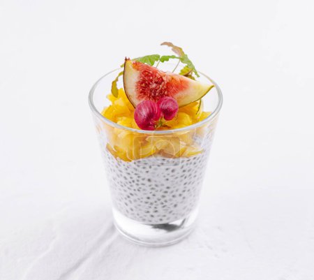 Elegant glass of chia seed pudding adorned with ripe fig, radish, and citrus slices