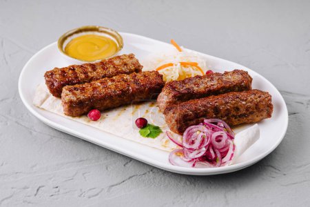 Juicy grilled kebabs served on a white plate with fresh salad and dipping sauce