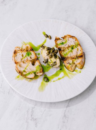 Elegant presentation of sliced chicken breast with a vibrant pesto sauce, garnished with capers