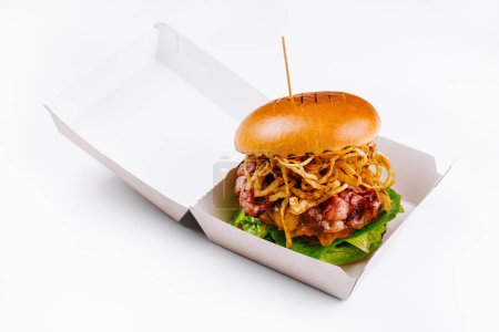 Deliciosa hamburguesa con tocino y cebolla dorada frita, presentada en un recipiente de papel