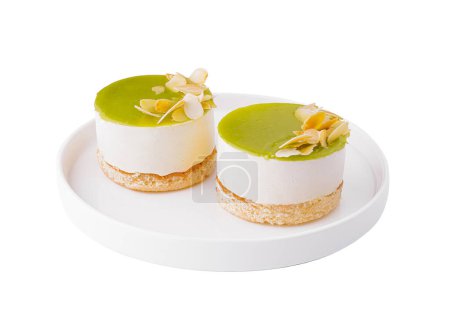 Photo for Two individual lime cheesecakes with almond slices on a white plate, isolated on white background - Royalty Free Image
