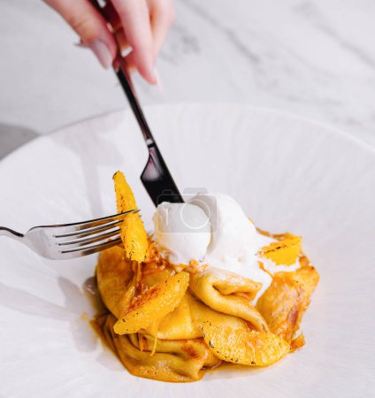 deliciosos panqueques postre cucharada de helado con guarnición de ralladura de naranja, tenedor en acción