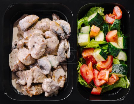 Poitrine de poulet saine avec sauce crémeuse et salade de jardin fraîche dans des boîtes de préparation de repas