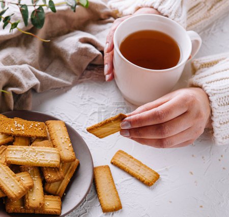 Person enjoying herbal tea with freshly baked biscuits on a serene tabletop