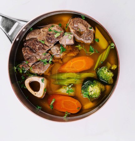 Top view of a delicious beef soup with vegetables in a pot, ready to serve