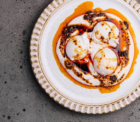 Top view of delicious poached eggs drizzled with a spicy sauce, served on an ornate white plate