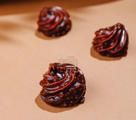 Elegant swirls of glossy chocolate staged on a beige surface with a minimalist aesthetic