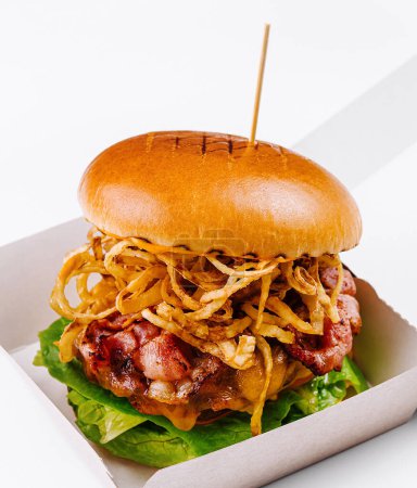 Delicious burger with bacon and golden fried onions, presented in a paper container