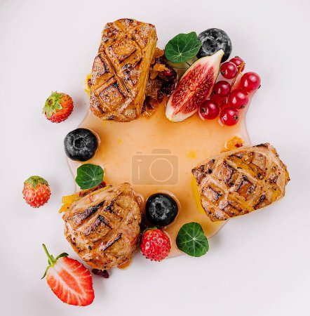 Draufsicht auf eine stilvolle Fleischplatte mit verschiedenen Beeren und Soße auf reinem weißen Hintergrund