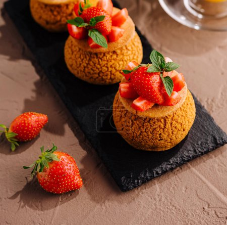 Gourmet tartlets topped with ripe strawberries and mint leaves, served with a glass of orange juice