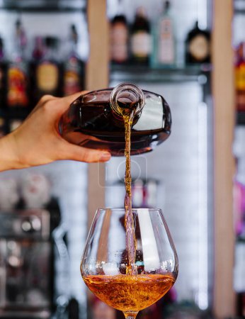Barman verser du whisky doré dans un verre élégant sur un comptoir de bar vibrant