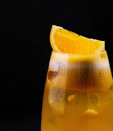 Close-up of a chilled orange cocktail garnished with a slice and served in a stylish glass