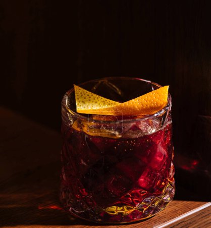 Classic cocktail adorned with a twist of citrus peel, presented in warm, intimate lighting