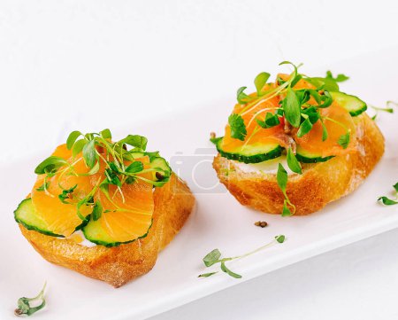 Elegant salmon canapes topped with microgreens on a white plate