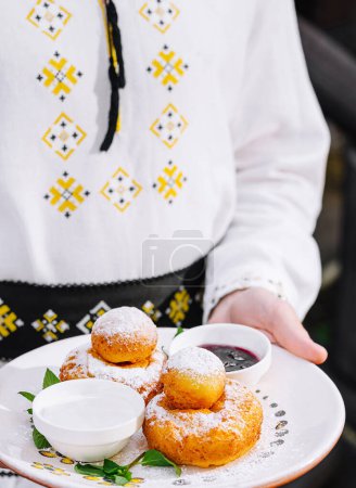 Close-up of a person in ethnic costume serving local sweet pastries with dipping sauces