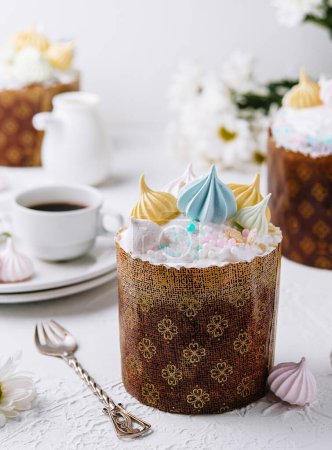 Traditional easter kulich topped with pastel frosting and merengues, served with tea