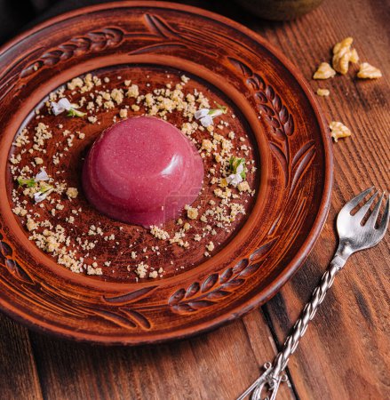 Aesthetic image of chocolate pudding topped with berry sorbet on a carved wooden plate, garnished with nuts