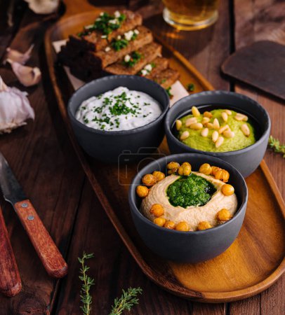 Photo for Appetizing selection of beer snacks with toasts and various dips on a rustic wooden serving board - Royalty Free Image
