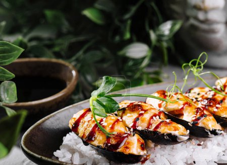 Fresh mussels with herbs and sauce served on a bed of rock salt, with green foliage backdrop