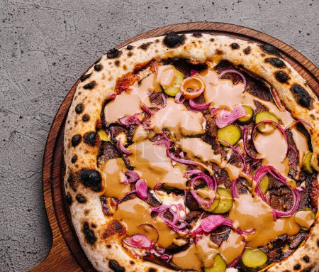 Artisanal vegan pizza with colorful toppings on a wooden board, set on a textured grey surface